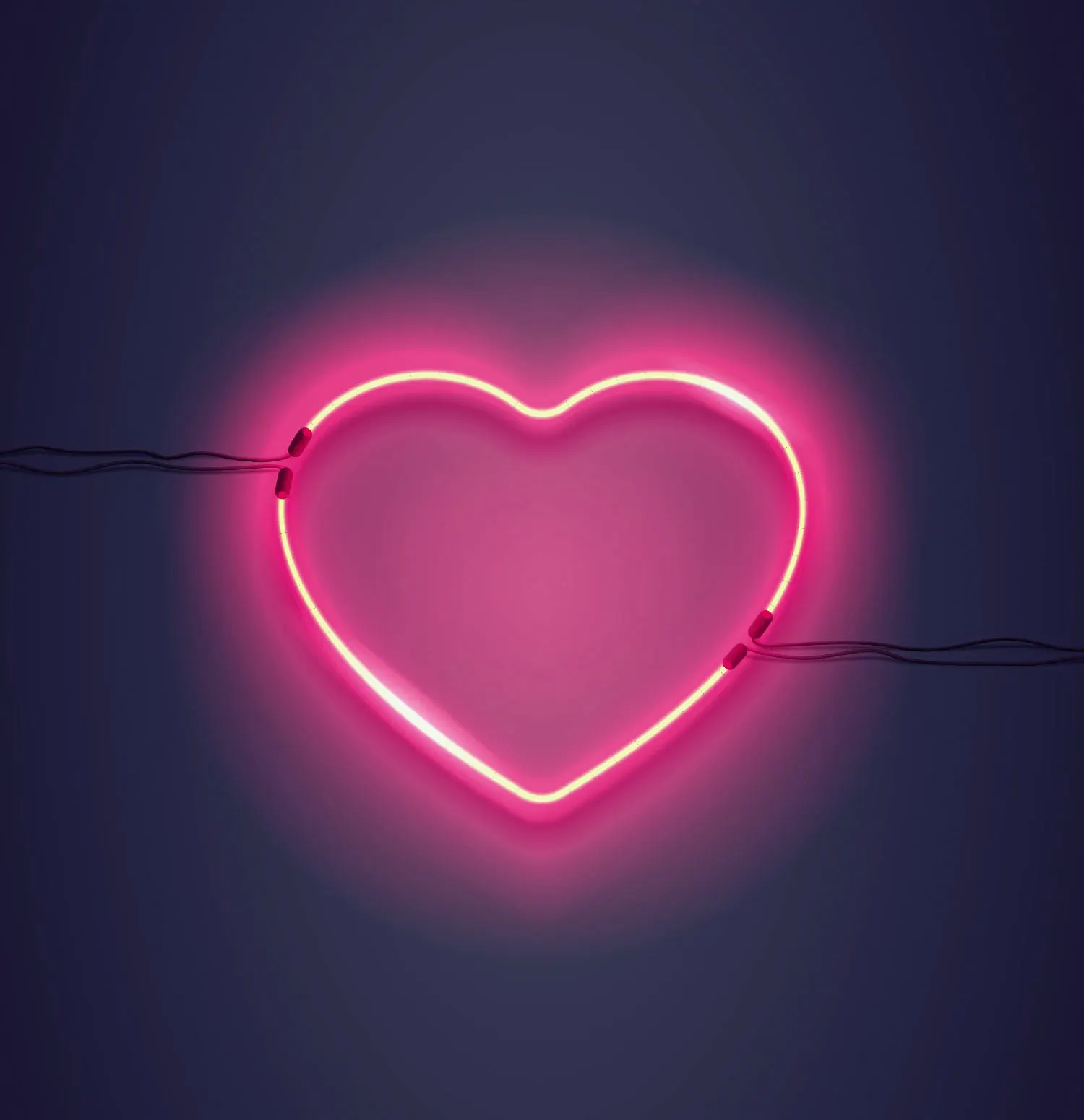 Glowing neon heart sign above a wedding reception dance floor